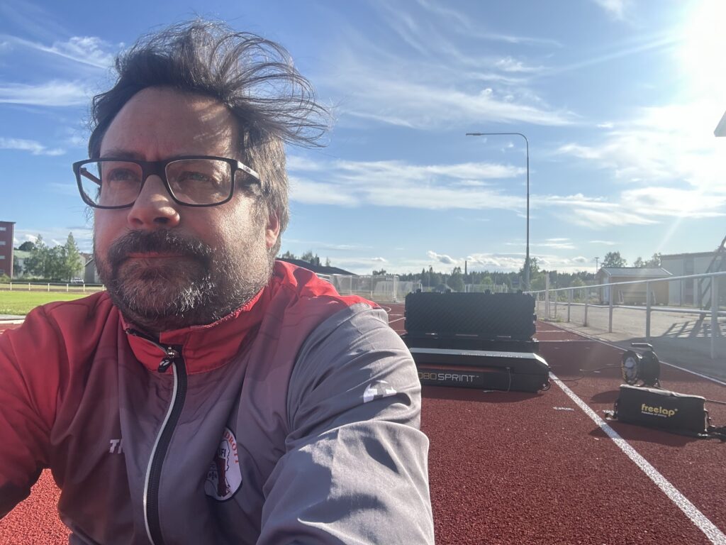 Marcus Lehto sitter på löparbanan med Freelap-utrustning och 1080 Sprint i bakgrunden under en solig dag på Acceleration Lab Uppsala.